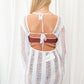 Long sleeved, sheer crochet mini dress with an open back in white.