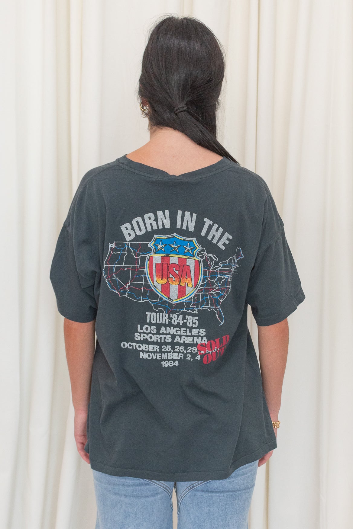 Black graphic tee featuring  Bruce Springsteen's Born in The USA Merch Tee. Crafted with the legendary pink cadillac and 'Born in the U.S.A.' tour logo,