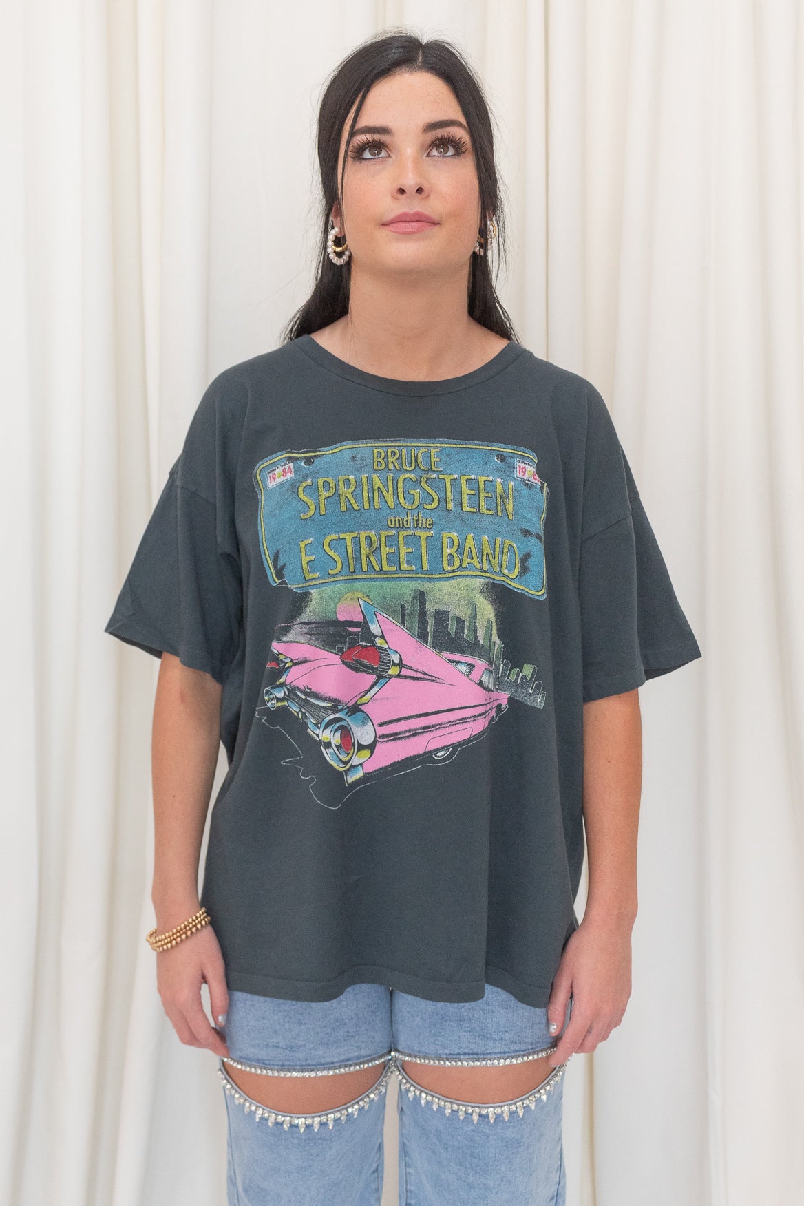 Black graphic tee featuring  Bruce Springsteen's Born in The USA Merch Tee. Crafted with the legendary pink cadillac and 'Born in the U.S.A.' tour logo,