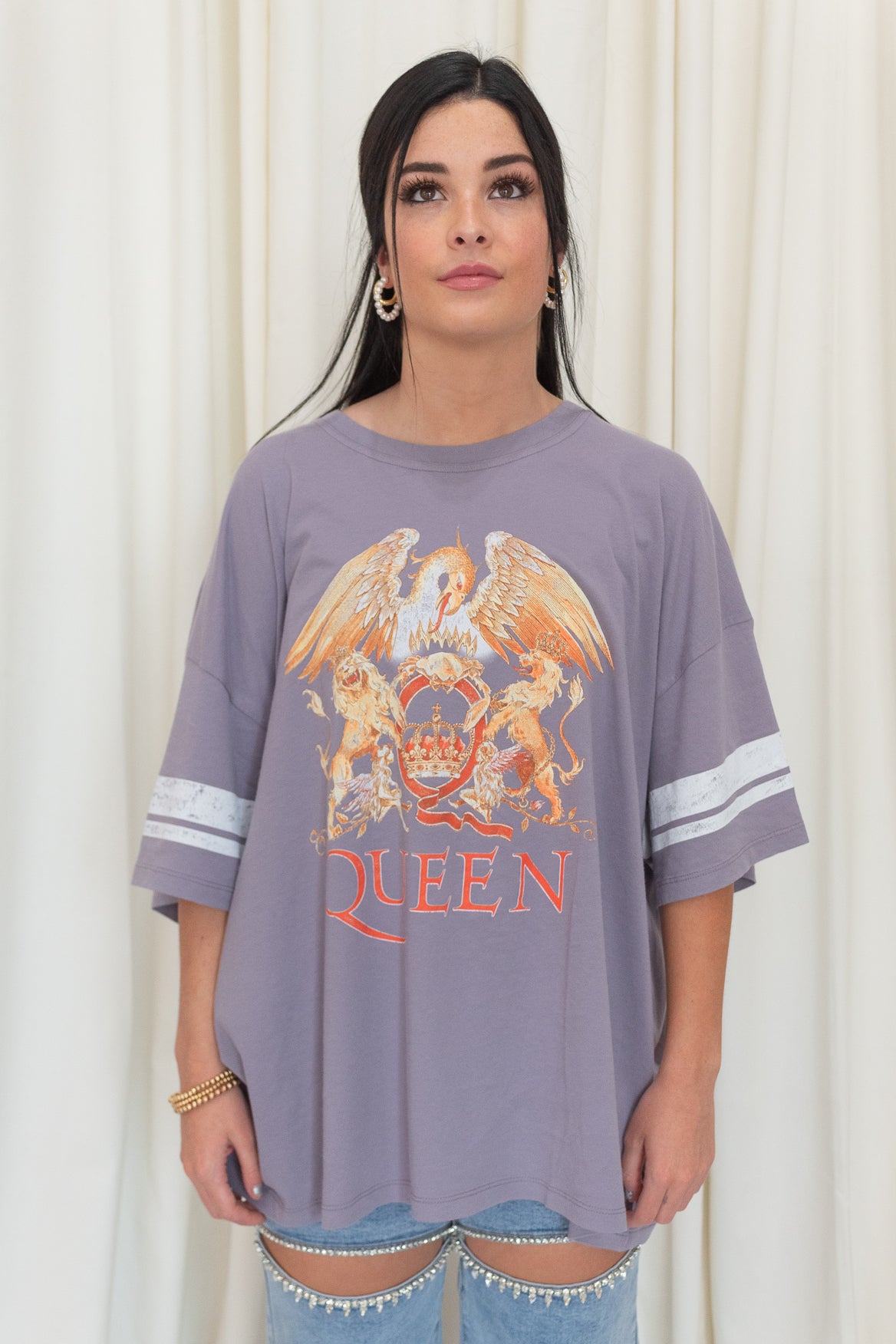 Light purple varsity t-shirt with an oversized fit featuring Queen and its iconic logo on the front. 
