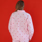 Person wearing a light pink outfit with red heart patterns against a red background
