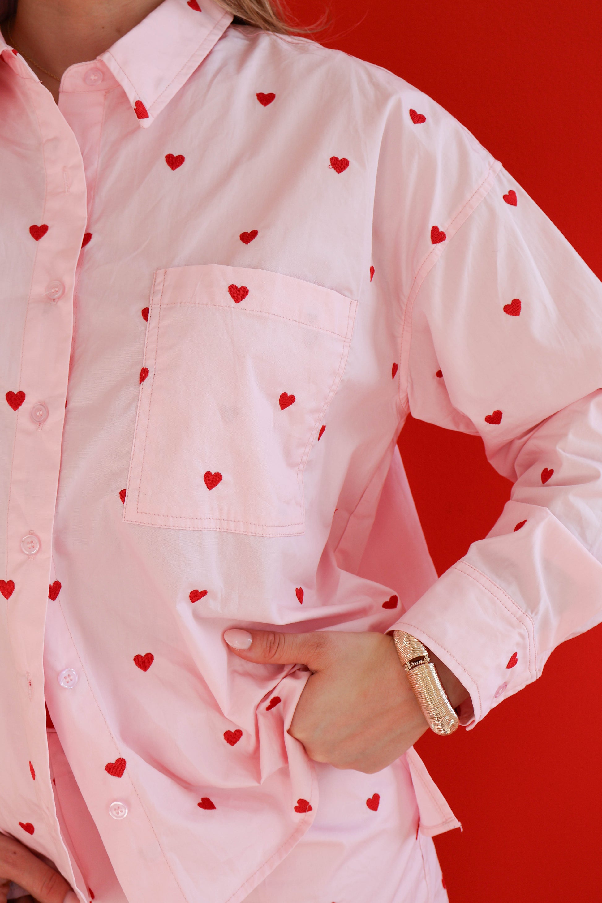 Pink shirt with red heart patterns on a red background
