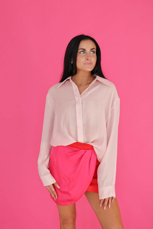 Woman wearing a light pink blouse and bright pink skirt against a pink background