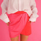Person wearing a white blouse and pink skirt against a pink background