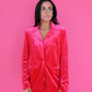 Woman wearing a pink velvet jacket against a pink background
