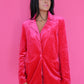 Woman wearing a pink velvet jacket against a pink background