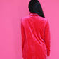 Person wearing a red velvet dress against a pink background
