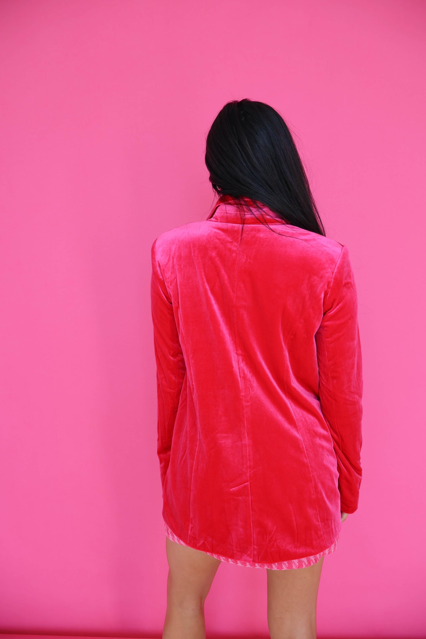 Person wearing a red velvet dress against a pink background