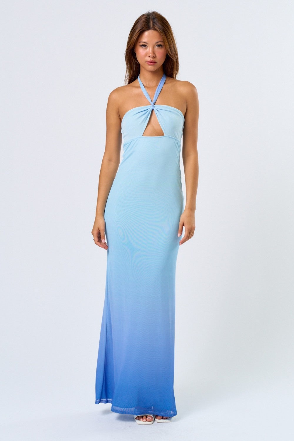 Woman wearing a blue ombré halter maxi dress with front cutout, standing against a plain white background.