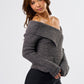 Woman wearing a gray off-shoulder sweater and black skirt on a white background