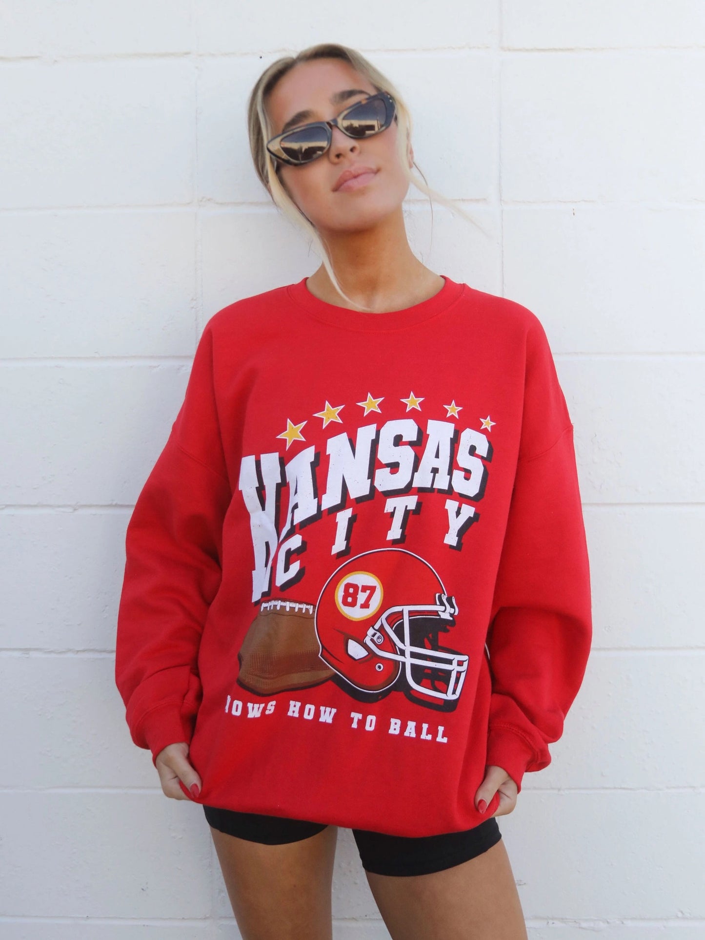 red sweatshirt with Kansas city knows how to ball on the front with a football and red helmet with 87 on helmet