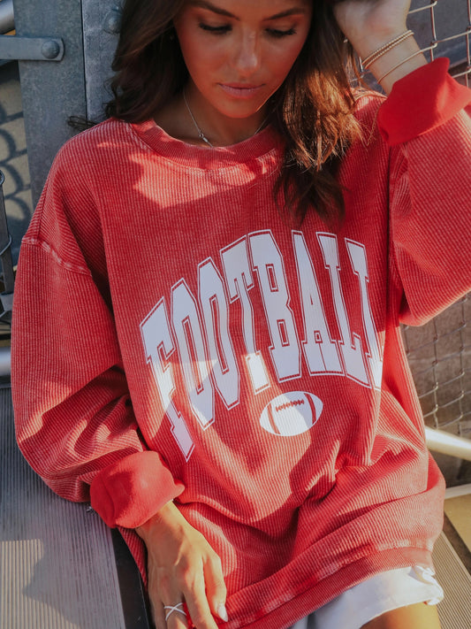 red corded crewneck sweatshirt with "Football" written in white with a small football graphic under