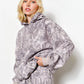 Woman wearing a gray patterned hoodie and pants on a white background