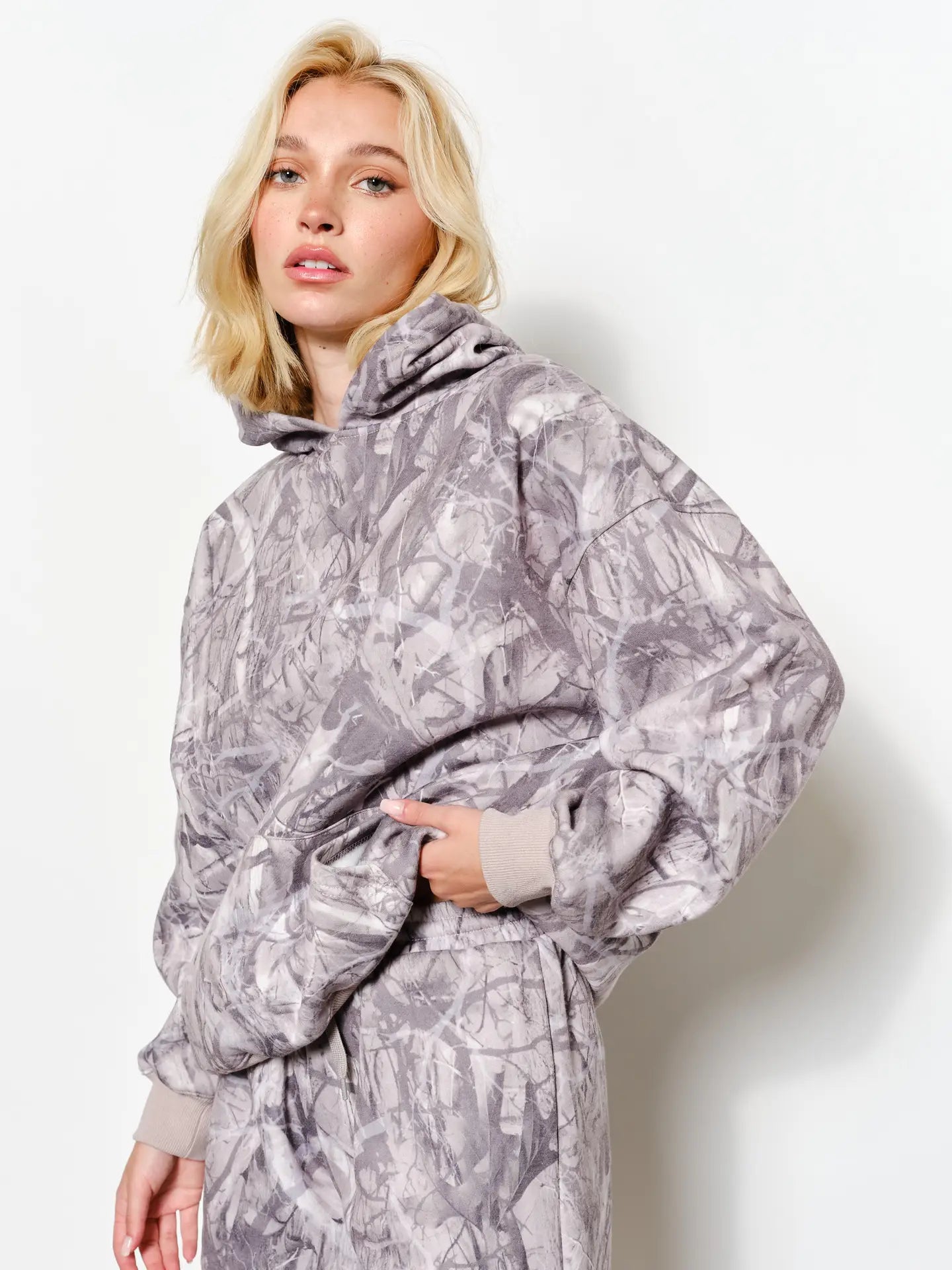 Woman wearing a gray patterned hoodie and pants on a white background