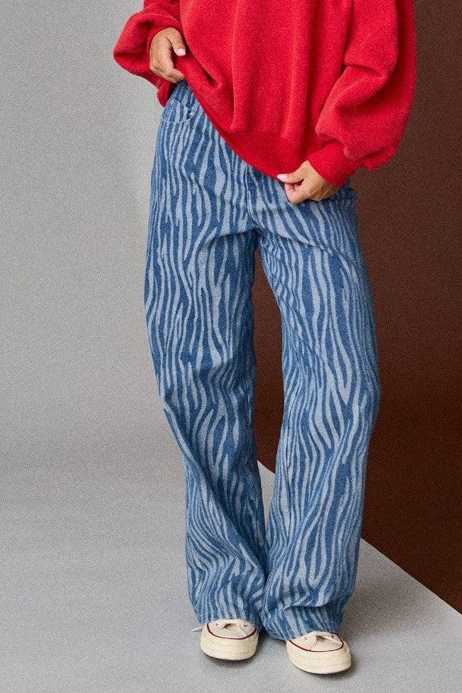 Person wearing blue patterned pants and a red sweater against a gradient background