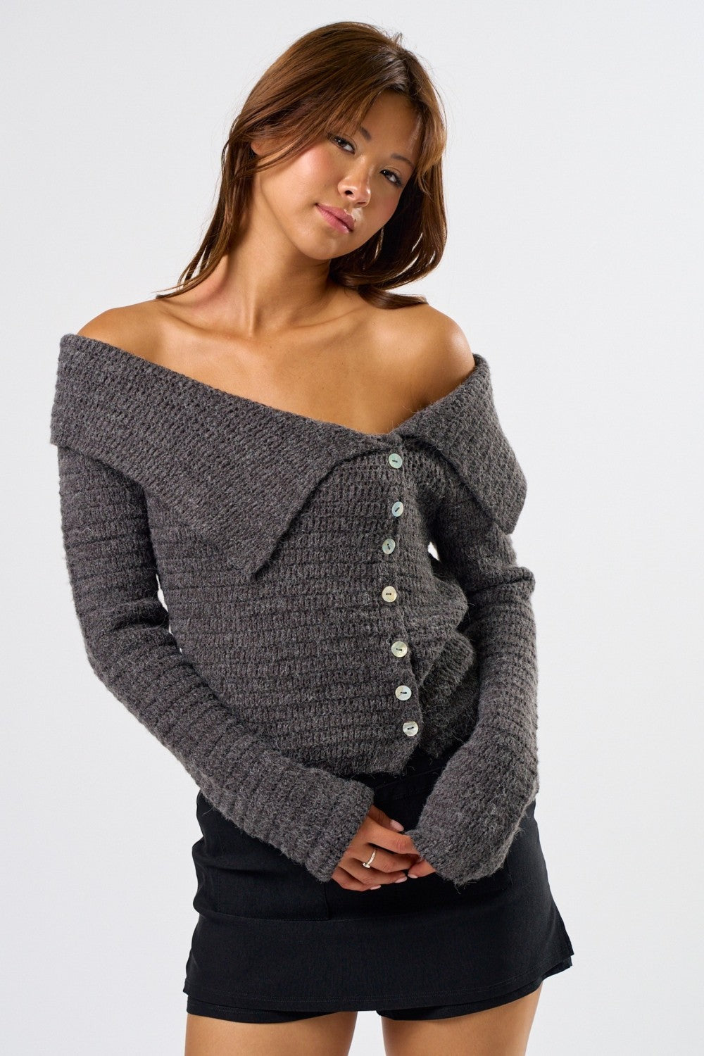 Woman wearing a gray off-shoulder knit cardigan on a white background