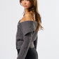 Woman wearing a gray off-shoulder sweater and black skirt on a white background